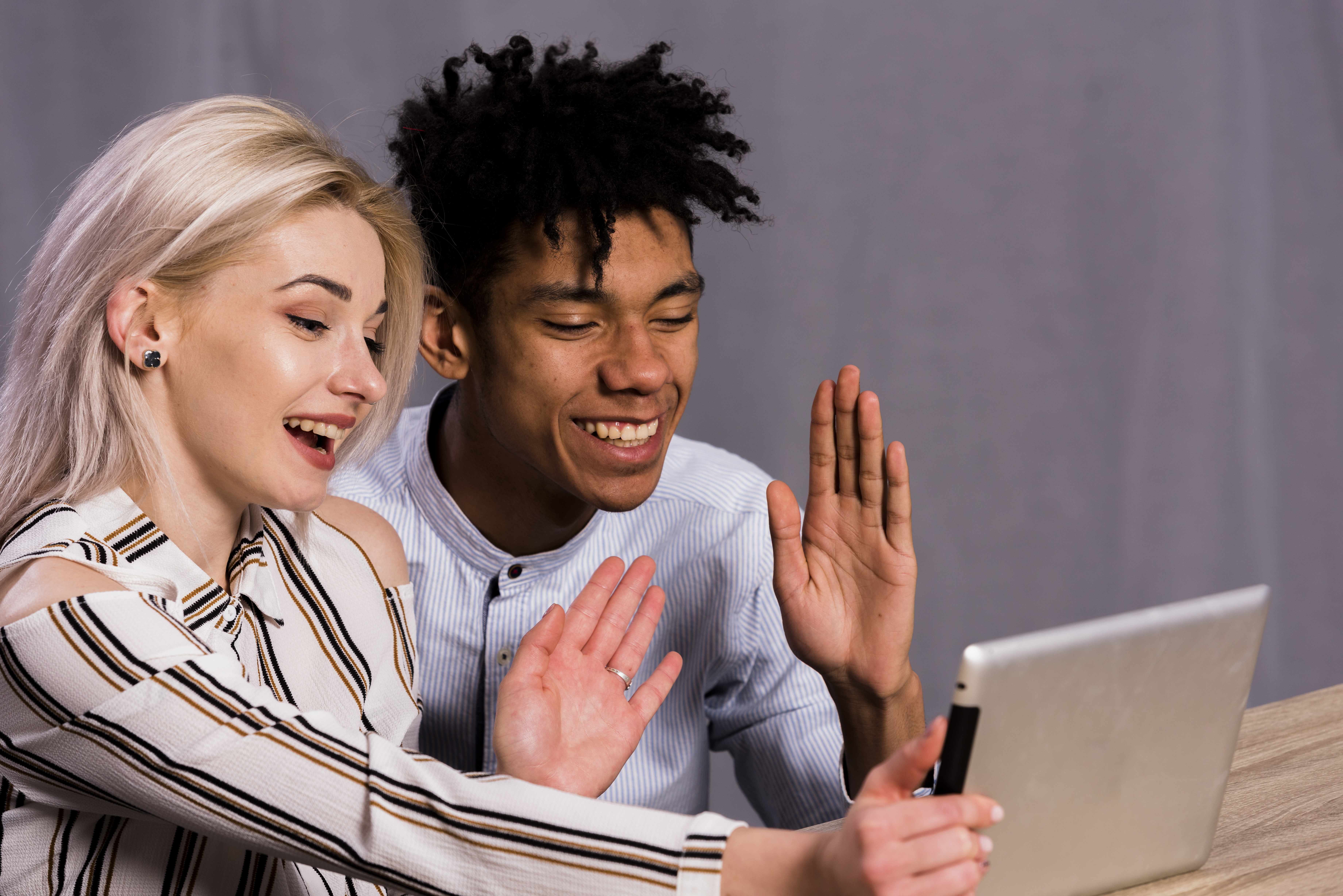 interracial-young-couple-making-video-call-digital-tablet-waving-their-hands