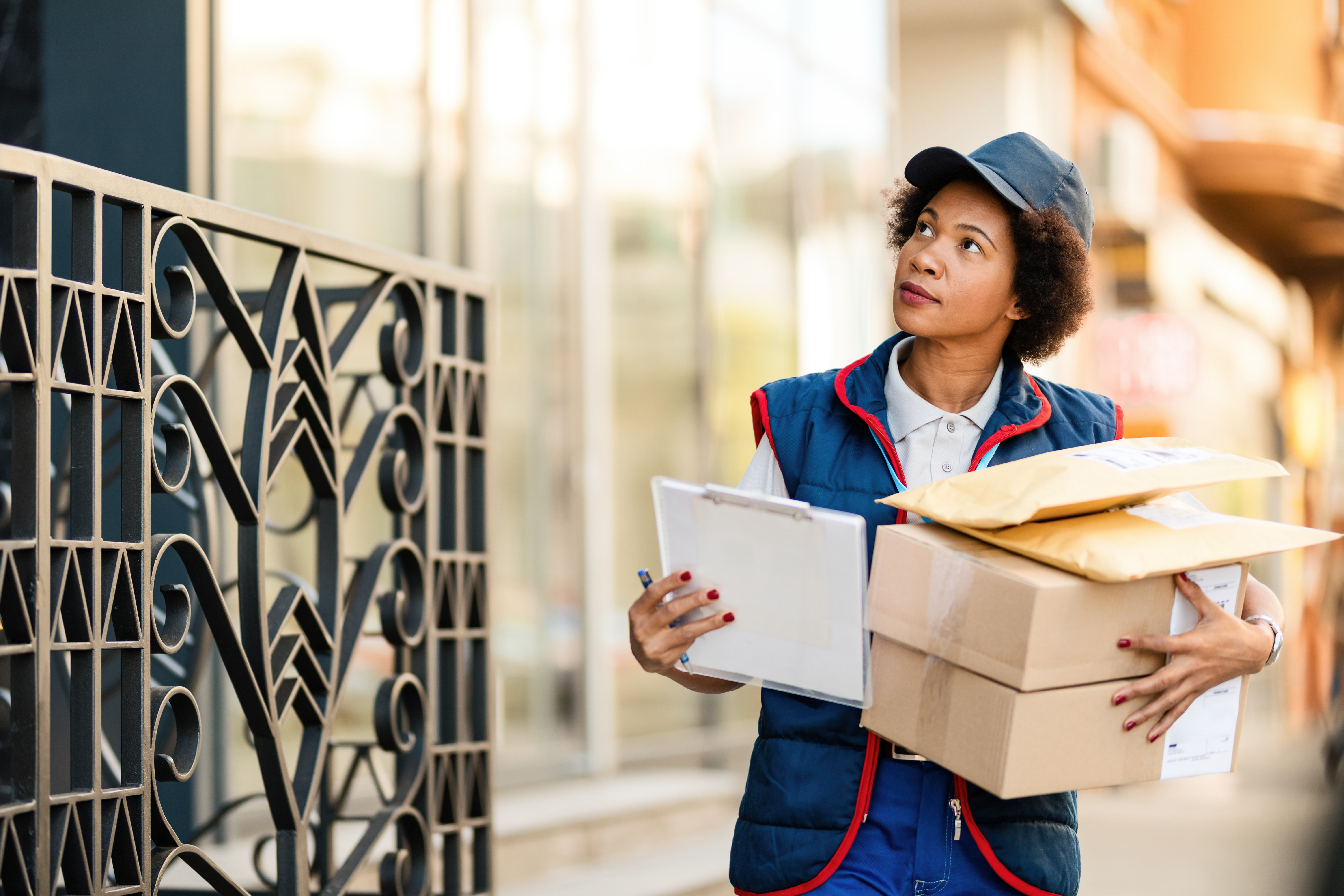 african-american-female-postal-worker-carrying-packages-while-delivering-them-residential-district
