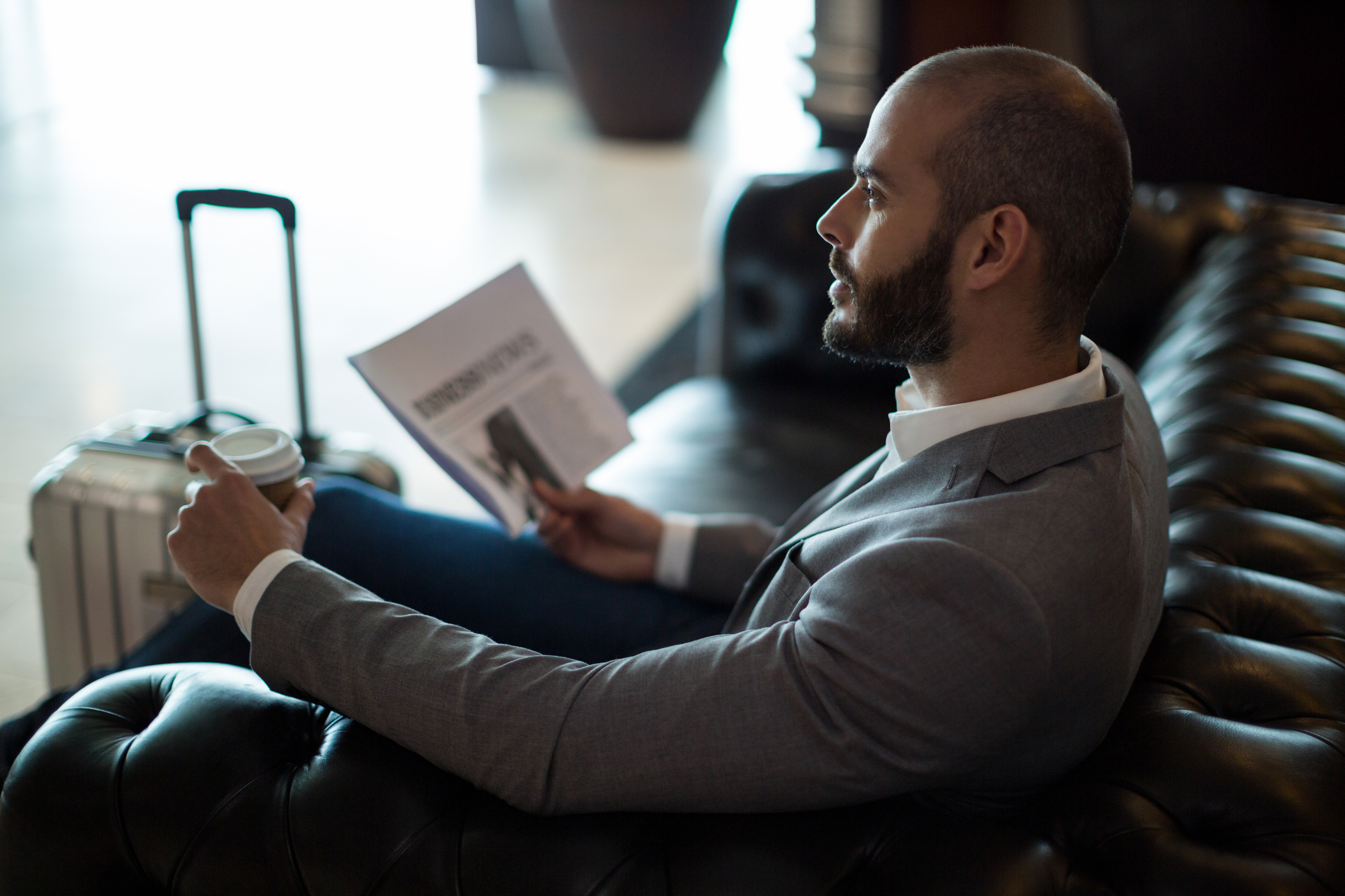 thoughtful-businessman-holding-newspaper-coffee-cup-waiting-area